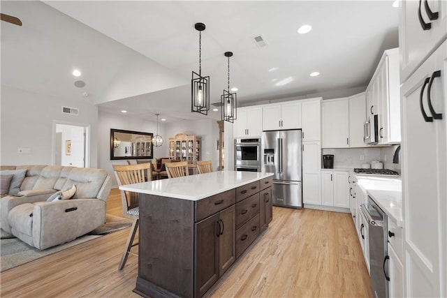 kitchen featuring open floor plan, dark brown cabinets, appliances with stainless steel finishes, and white cabinets