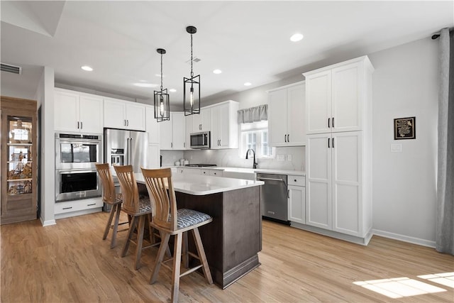 kitchen with a breakfast bar area, visible vents, a kitchen island, stainless steel appliances, and light countertops