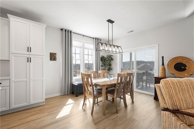 dining space with baseboards, visible vents, and light wood-type flooring