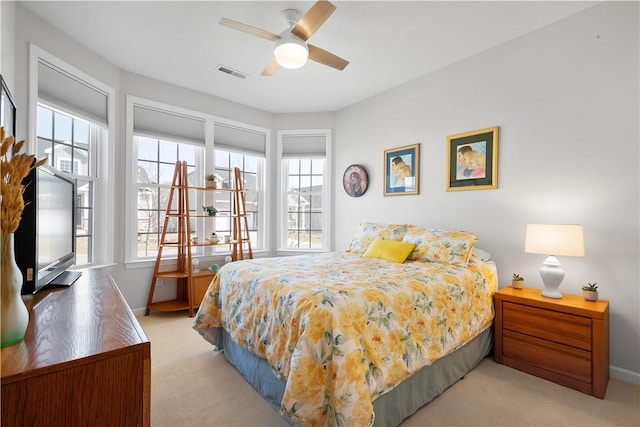 bedroom featuring visible vents, baseboards, light colored carpet, and a ceiling fan