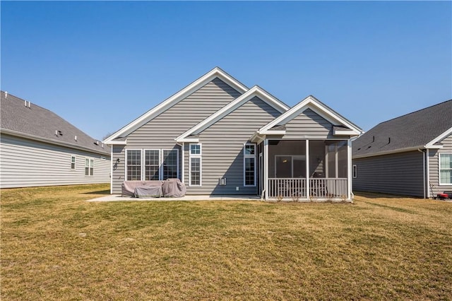 rear view of property featuring a patio area, a lawn, and a sunroom