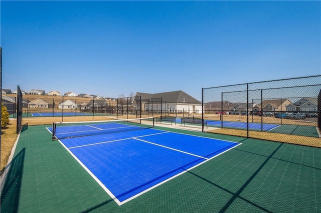 view of tennis court with fence and a residential view