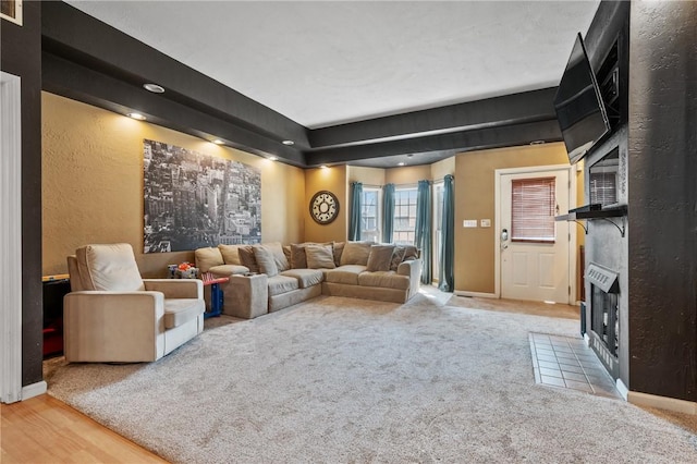 living area featuring visible vents, a fireplace with flush hearth, carpet, baseboards, and a textured wall