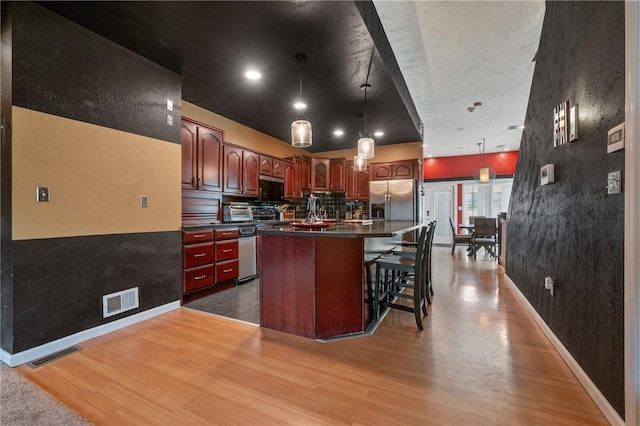 kitchen featuring stainless steel fridge, dark countertops, wood finished floors, and visible vents