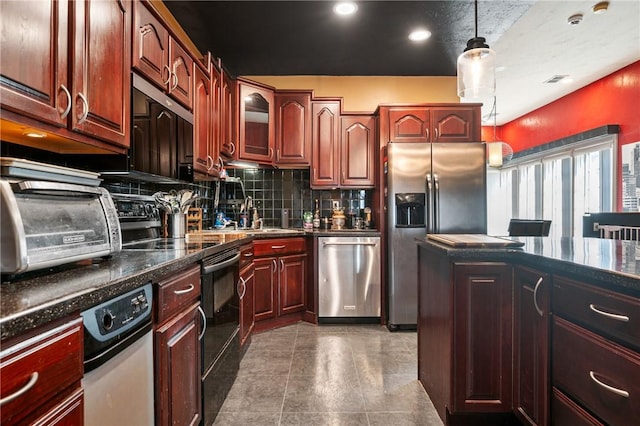 kitchen with a sink, tasteful backsplash, appliances with stainless steel finishes, glass insert cabinets, and hanging light fixtures