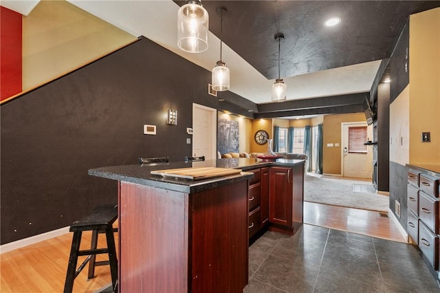 kitchen with a kitchen island, dark countertops, open floor plan, baseboards, and dark brown cabinets