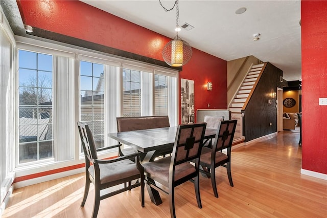 dining space featuring stairway, light wood-style flooring, baseboards, and visible vents