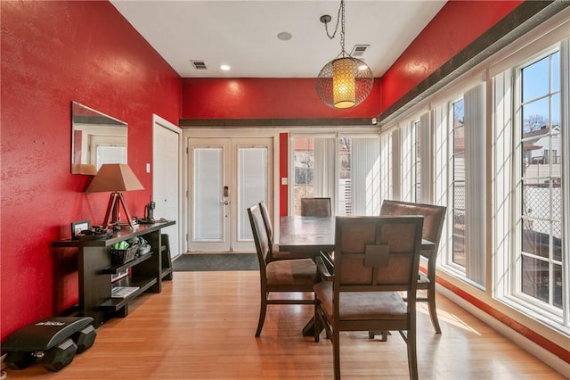 dining area with visible vents, a healthy amount of sunlight, french doors, and wood finished floors