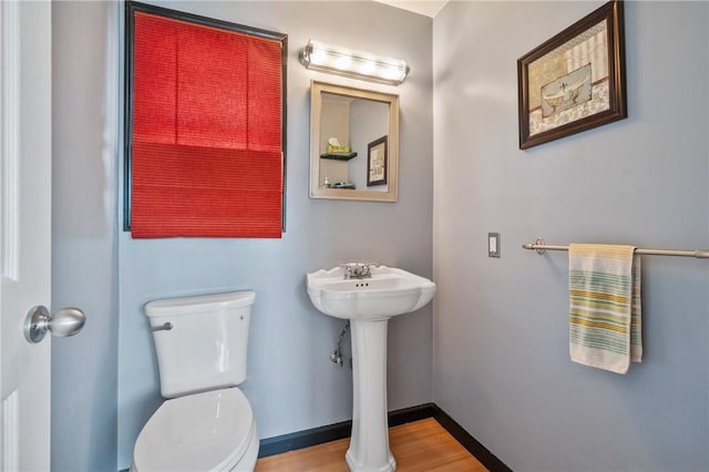 bathroom featuring a sink, toilet, baseboards, and wood finished floors