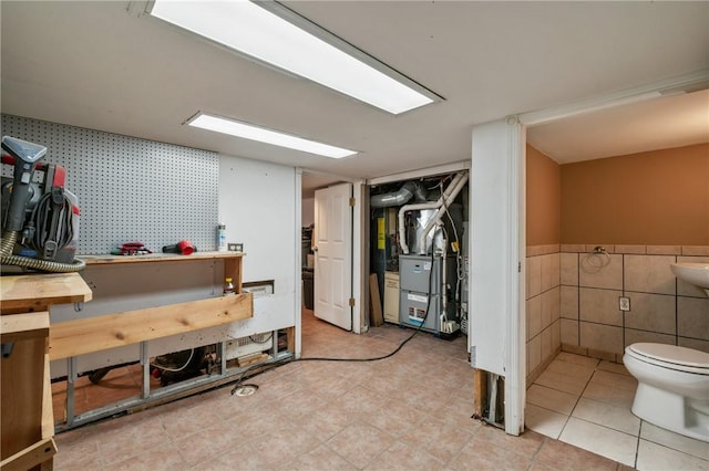 basement featuring heating unit, a workshop area, wainscoting, and wallpapered walls