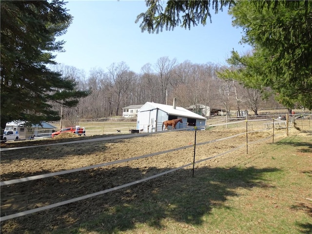 view of yard featuring an outbuilding, a rural view, and fence