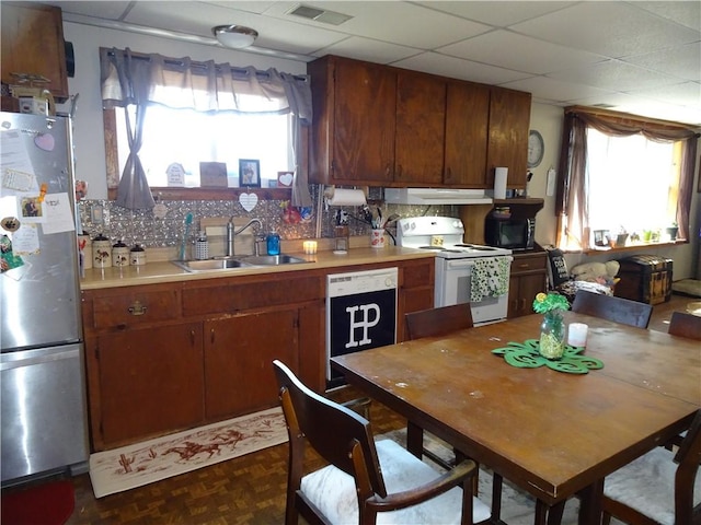 kitchen with visible vents, a healthy amount of sunlight, freestanding refrigerator, white electric range oven, and a sink