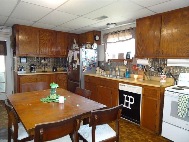 kitchen featuring white range with electric cooktop, under cabinet range hood, dishwashing machine, freestanding refrigerator, and a sink