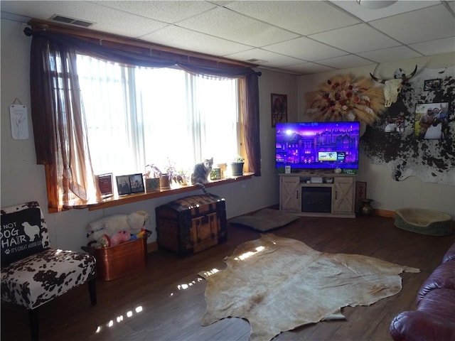 living room with wood finished floors, visible vents, and a paneled ceiling