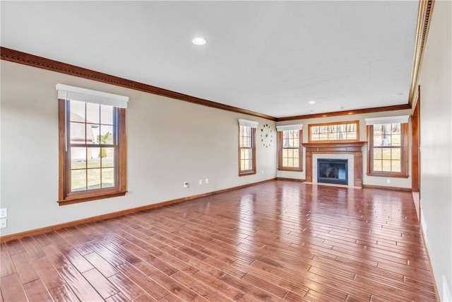 unfurnished living room featuring crown molding, baseboards, a tiled fireplace, recessed lighting, and wood finished floors