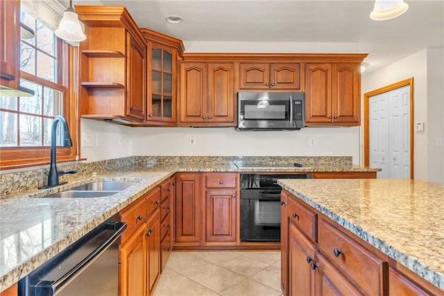 kitchen featuring black appliances, light stone counters, light tile patterned floors, and a sink