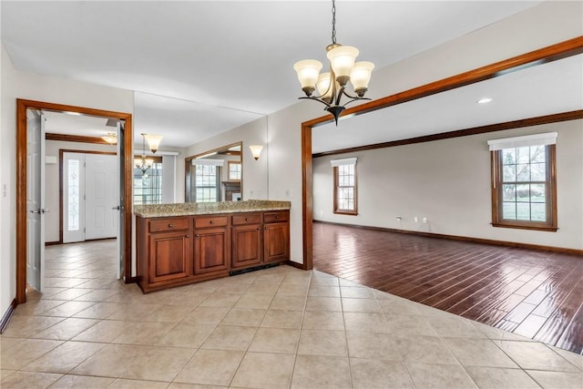 kitchen with brown cabinetry, a notable chandelier, a healthy amount of sunlight, and open floor plan