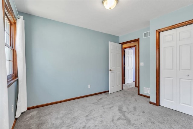 unfurnished bedroom with a closet, multiple windows, visible vents, and carpet floors