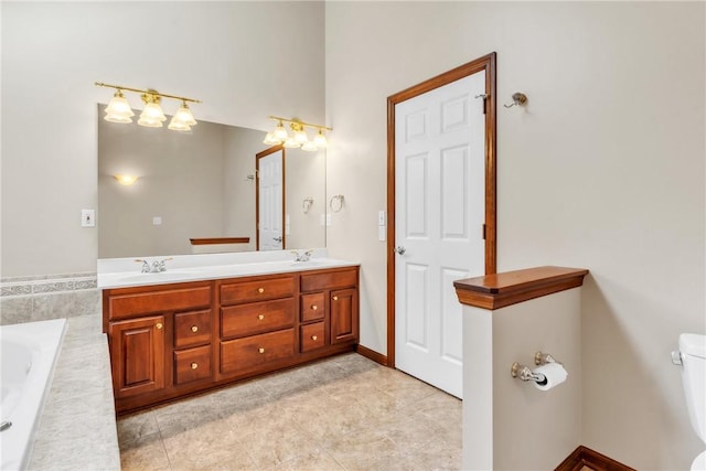 bathroom with double vanity, tile patterned floors, tiled tub, and a sink