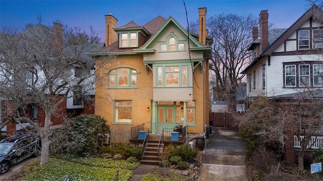 view of front of home with french doors, brick siding, and a chimney