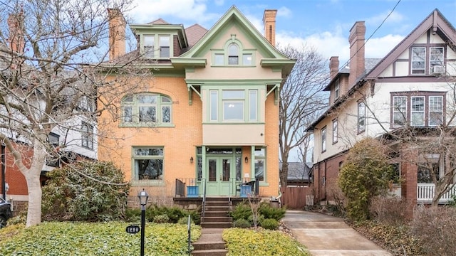 view of front of home featuring french doors, brick siding, and a chimney