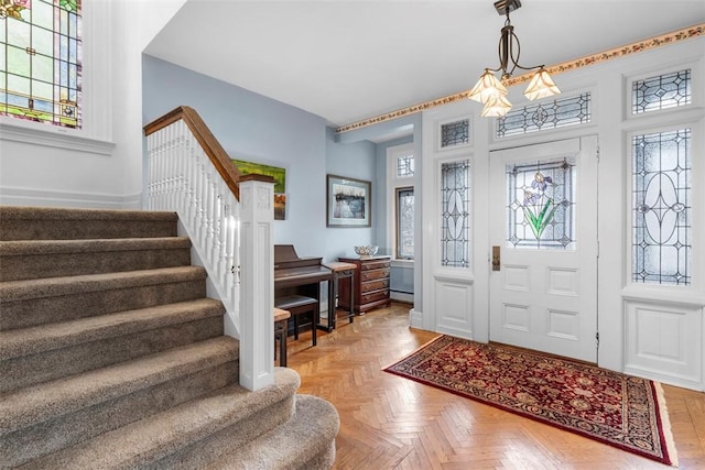 foyer featuring stairway, baseboard heating, and a healthy amount of sunlight