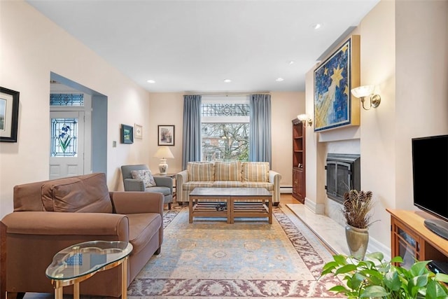 living room featuring a fireplace with flush hearth, recessed lighting, and baseboards