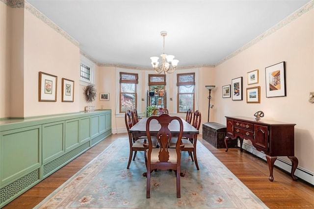 dining space with crown molding, a notable chandelier, and light wood-type flooring