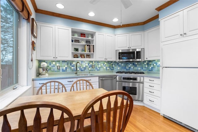 kitchen featuring light wood-style flooring, a sink, white cabinetry, stainless steel appliances, and light countertops