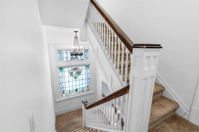 staircase featuring baseboards, carpet, and a chandelier