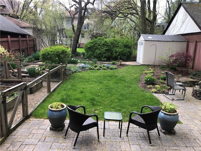 view of yard featuring a fenced backyard, a garden, an outbuilding, a storage unit, and a patio