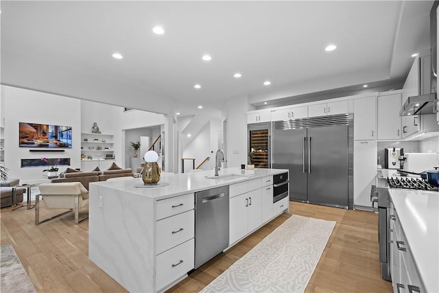 kitchen featuring a sink, light wood-style flooring, a center island with sink, and stainless steel appliances