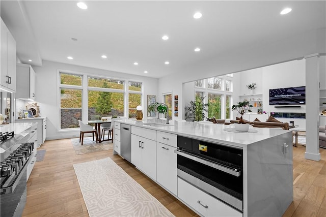 kitchen with a sink, a spacious island, recessed lighting, stainless steel appliances, and light wood-style floors