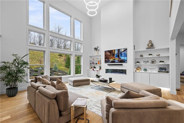 living area featuring a high ceiling, baseboards, and light wood-type flooring