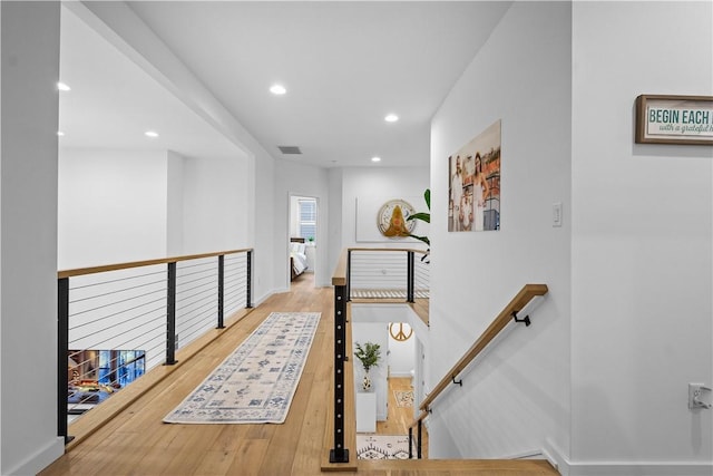 hallway with visible vents, an upstairs landing, hardwood / wood-style flooring, recessed lighting, and baseboards