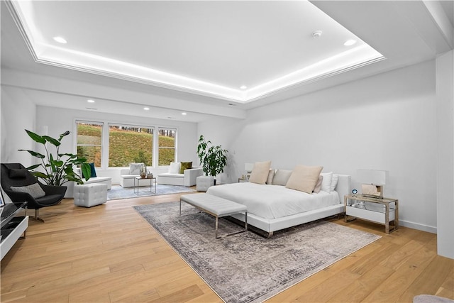 bedroom with recessed lighting, baseboards, light wood-style floors, and a tray ceiling