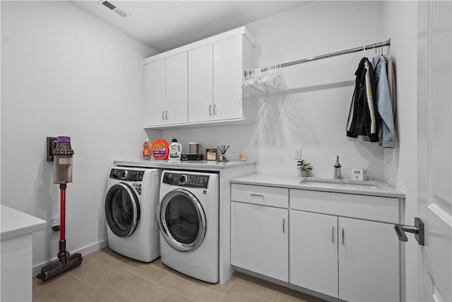 washroom featuring visible vents, a sink, washer and dryer, cabinet space, and baseboards