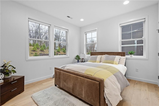 bedroom featuring visible vents, baseboards, and light wood finished floors