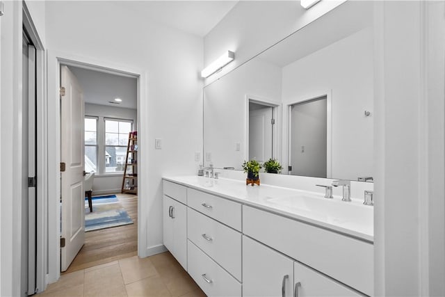 full bathroom with a sink, baseboards, double vanity, and tile patterned floors