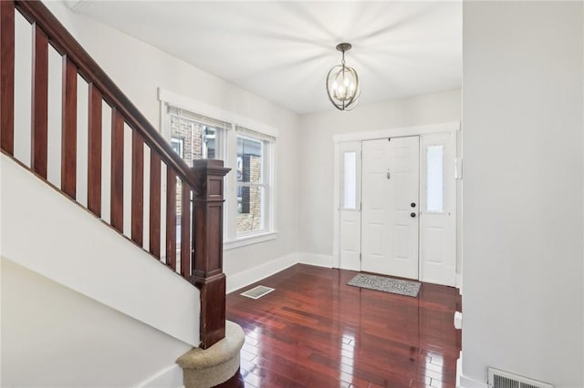 foyer with hardwood / wood-style flooring, stairway, visible vents, and a chandelier