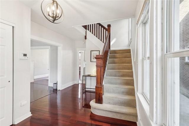 staircase with a chandelier, baseboards, and hardwood / wood-style flooring