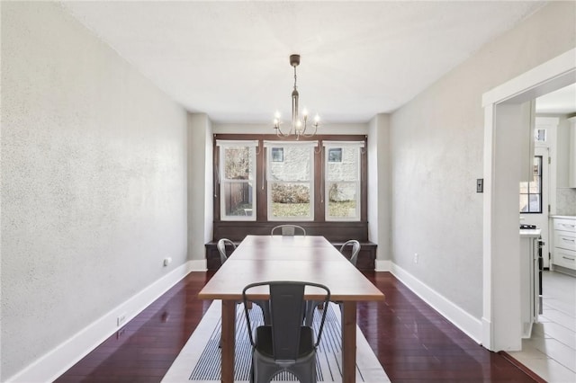 dining space featuring wood finished floors, baseboards, and a chandelier