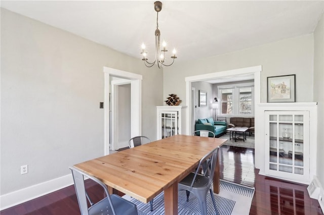 dining space with a chandelier, dark wood-style floors, and baseboards