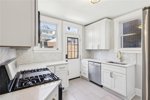 kitchen featuring appliances with stainless steel finishes, white cabinetry, light countertops, and a sink