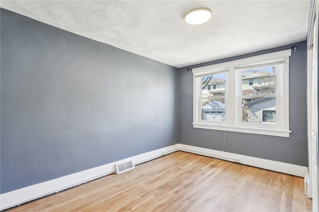 spare room featuring visible vents, baseboards, and wood finished floors