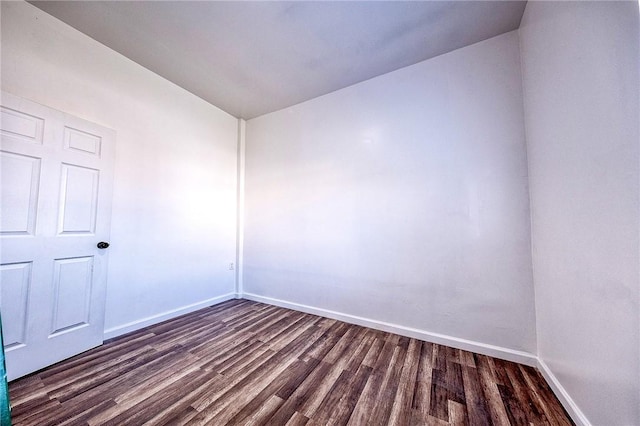 spare room with dark wood-type flooring and baseboards