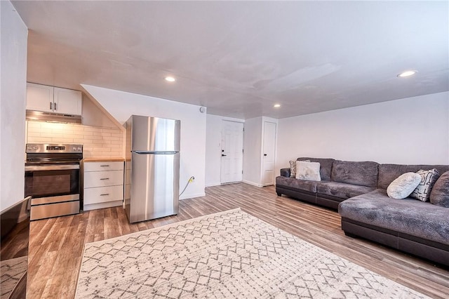 living room featuring recessed lighting, light wood-type flooring, and baseboards