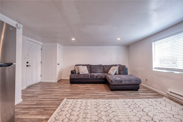 living room with recessed lighting, a baseboard heating unit, baseboards, and wood finished floors