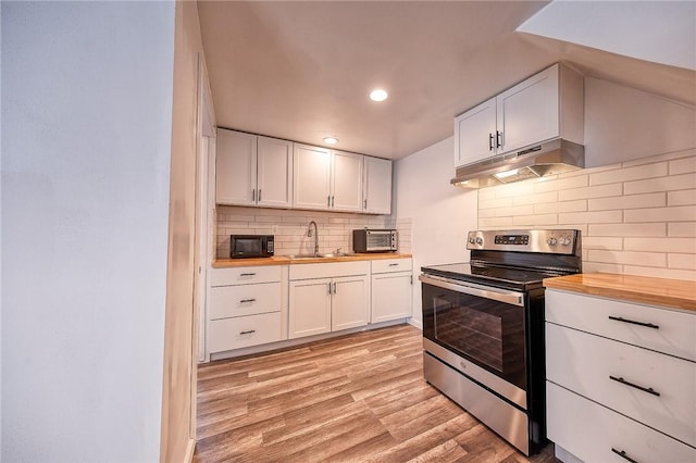 kitchen featuring stainless steel electric stove, butcher block countertops, a sink, black microwave, and under cabinet range hood