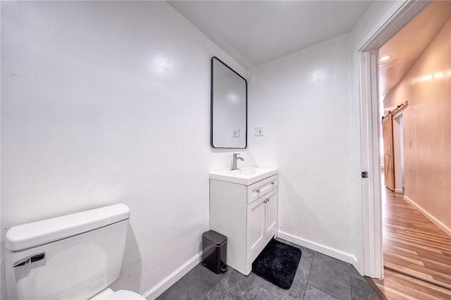 bathroom with baseboards, toilet, and vanity